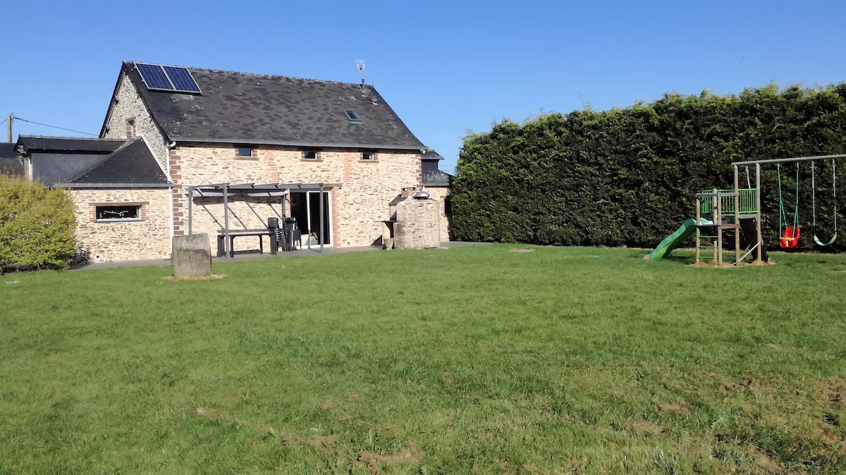 Stone house with solar panels and children's play area.