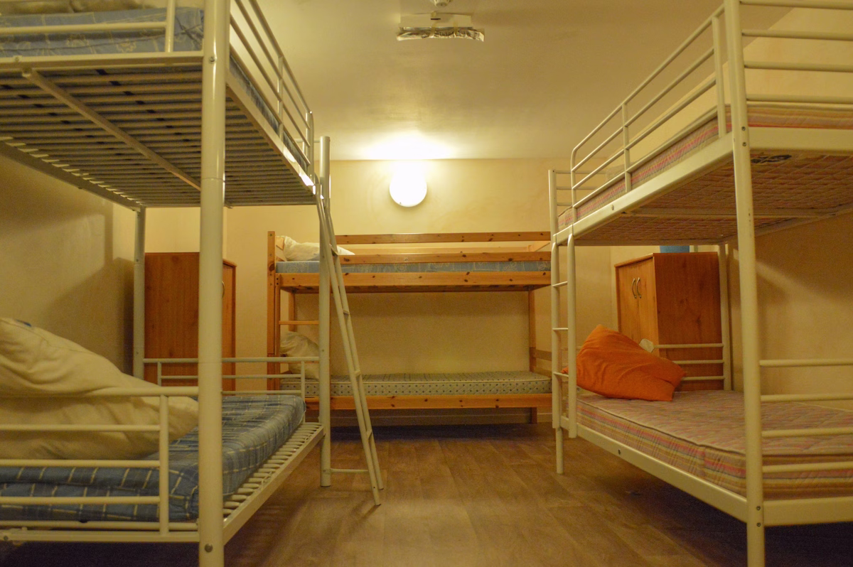 Hostel room with bunk beds and wooden floor.
