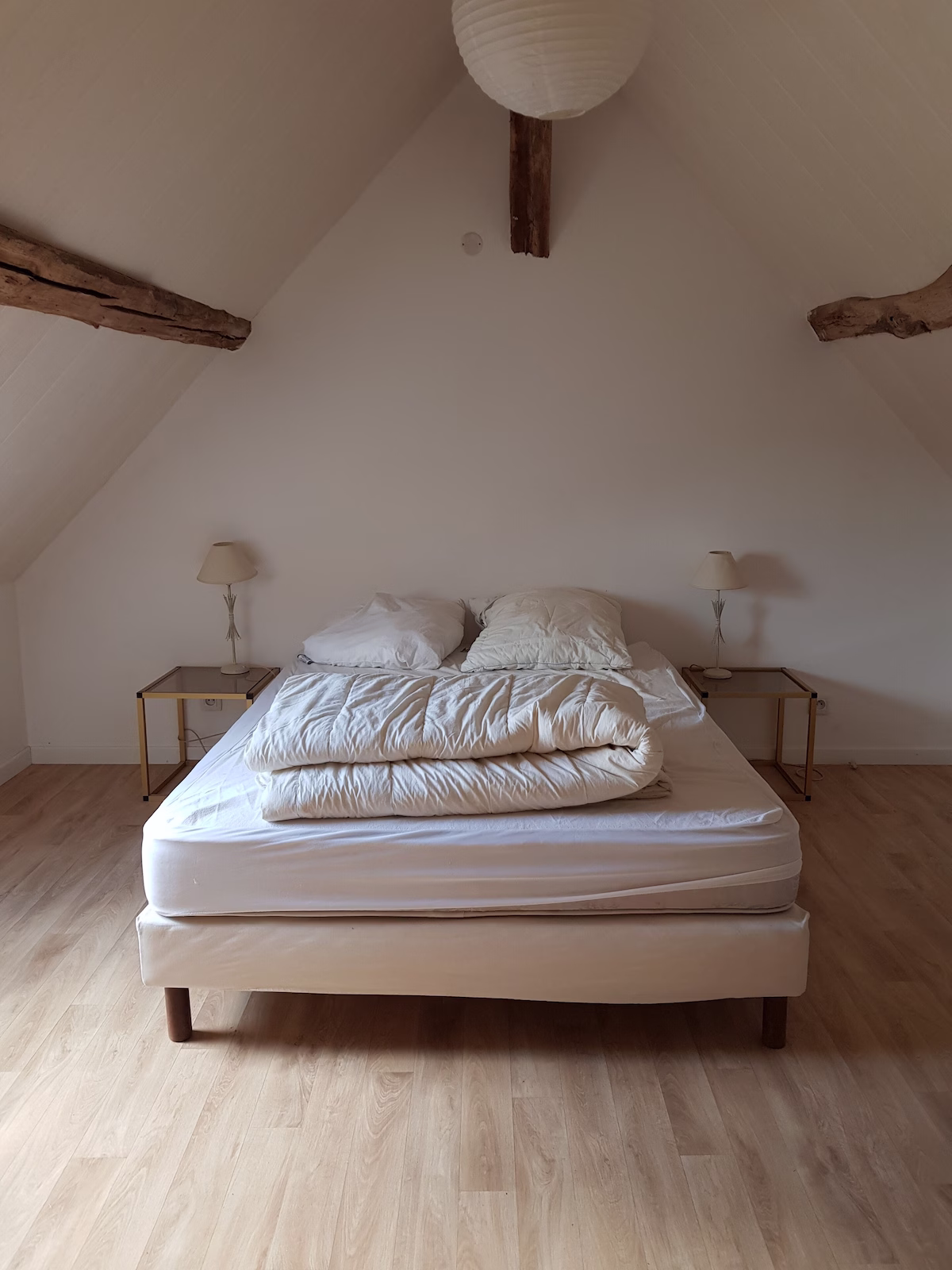 Minimalist attic bedroom with double bed and lamps.