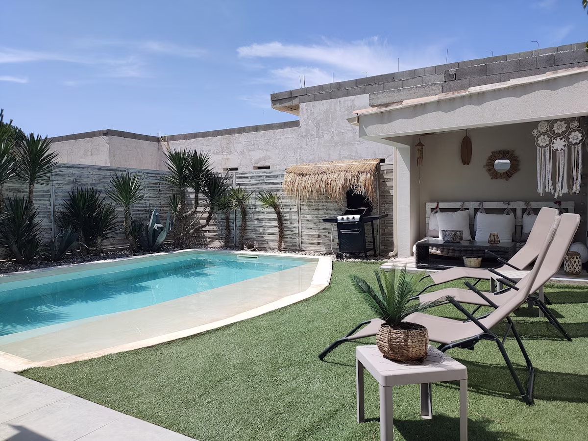 Backyard with pool, loungers, and shaded seating area.