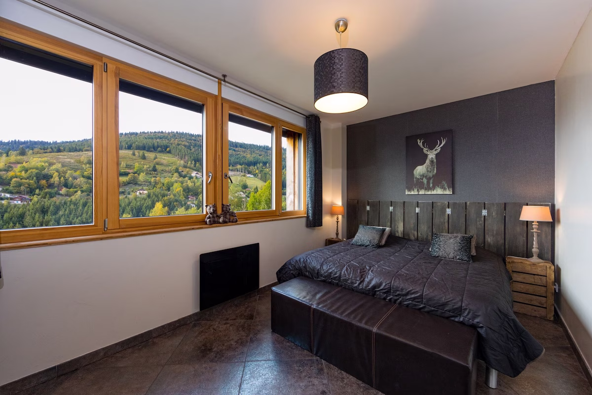 Cosy bedroom with forest view and large windows.