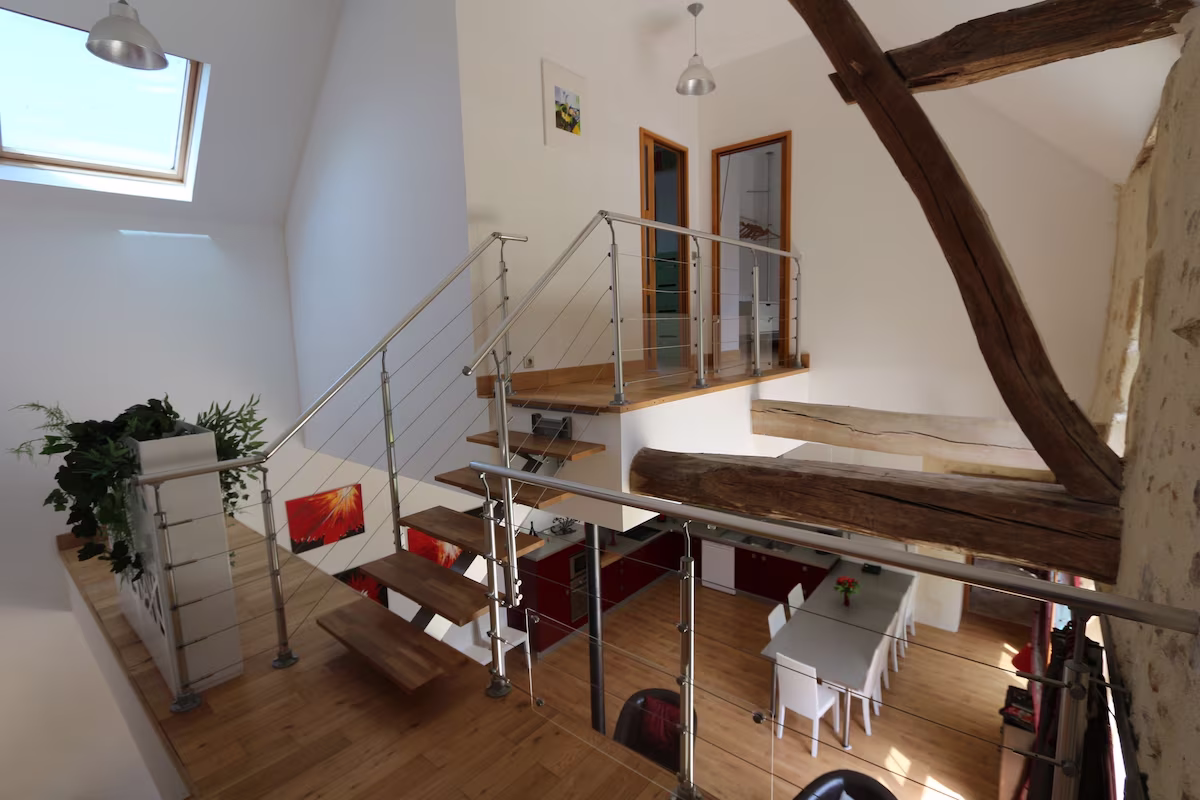 Modern open-plan loft with wooden beams and stairs.