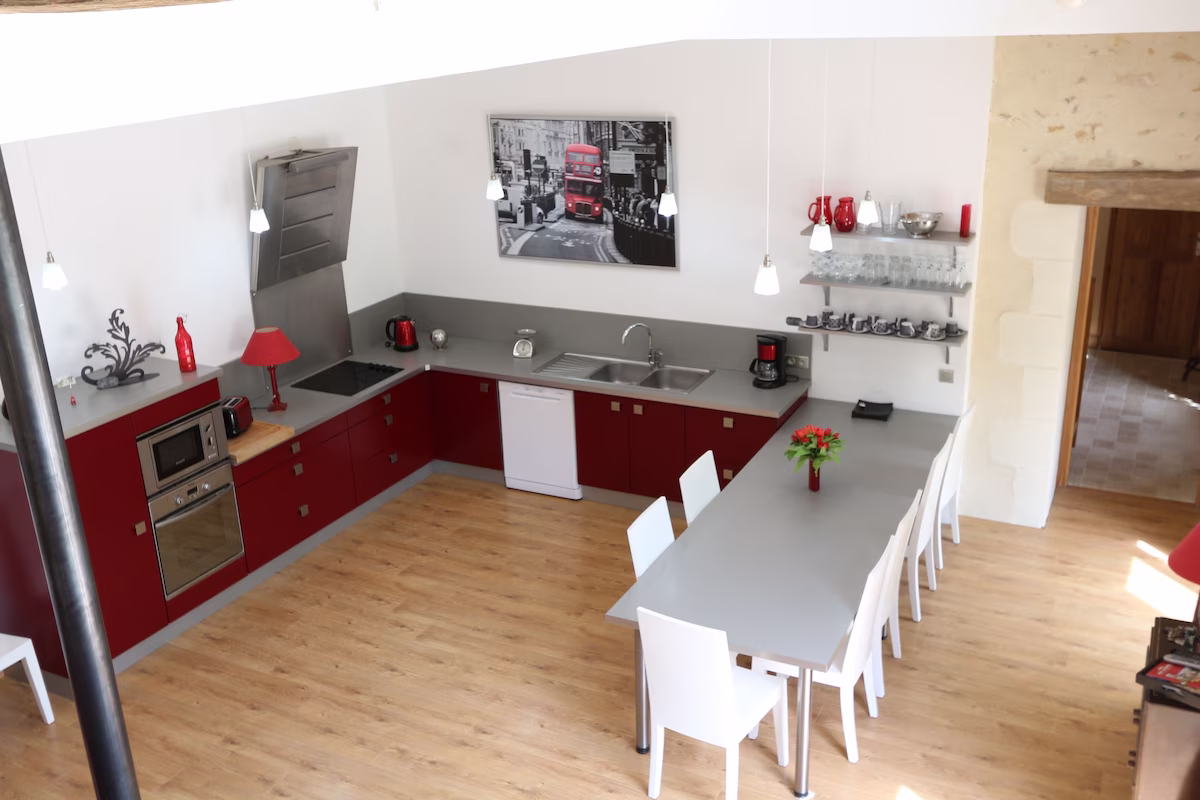 Modern kitchen with red cabinets and dining table.