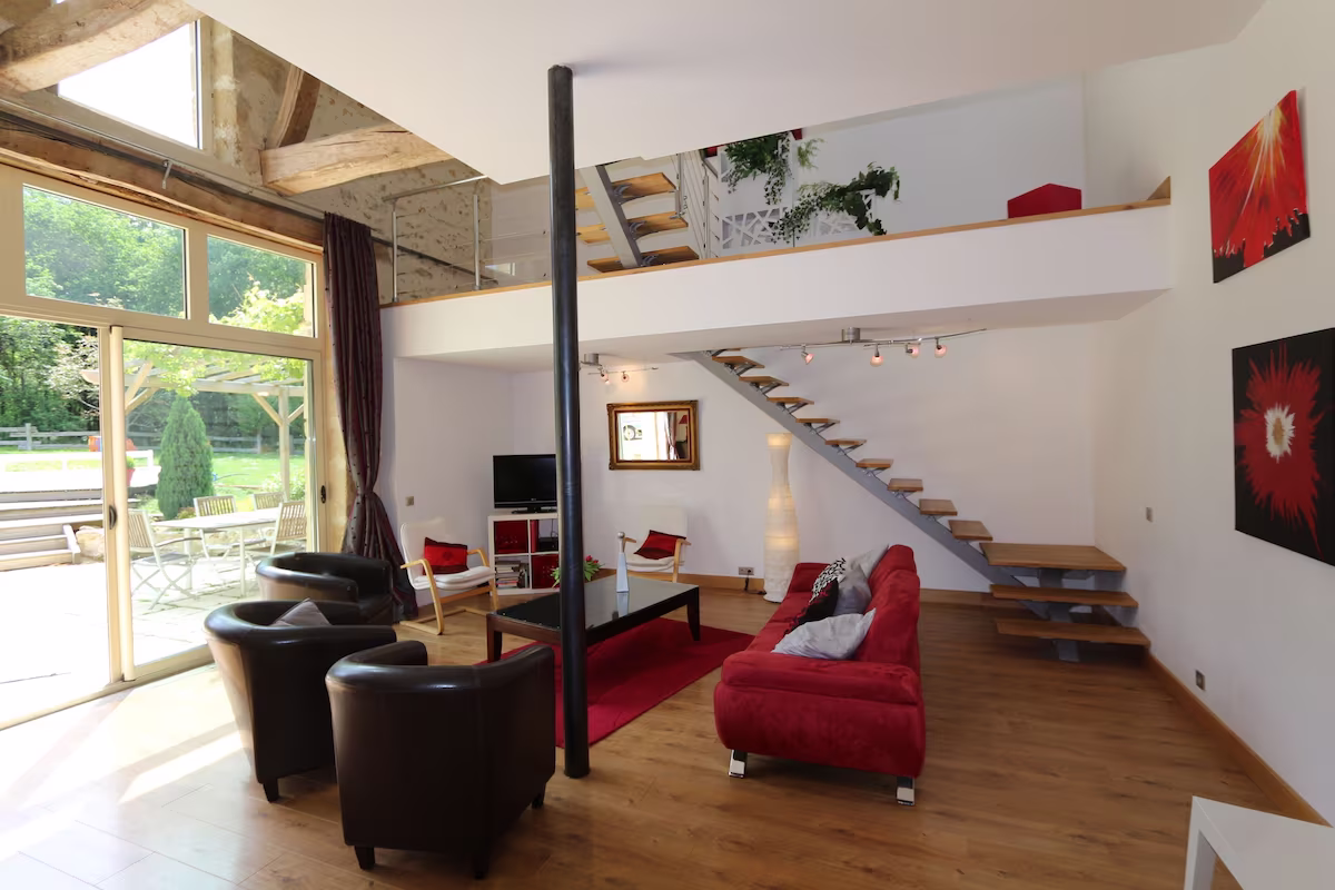 Modern open-plan living room with mezzanine and large windows.