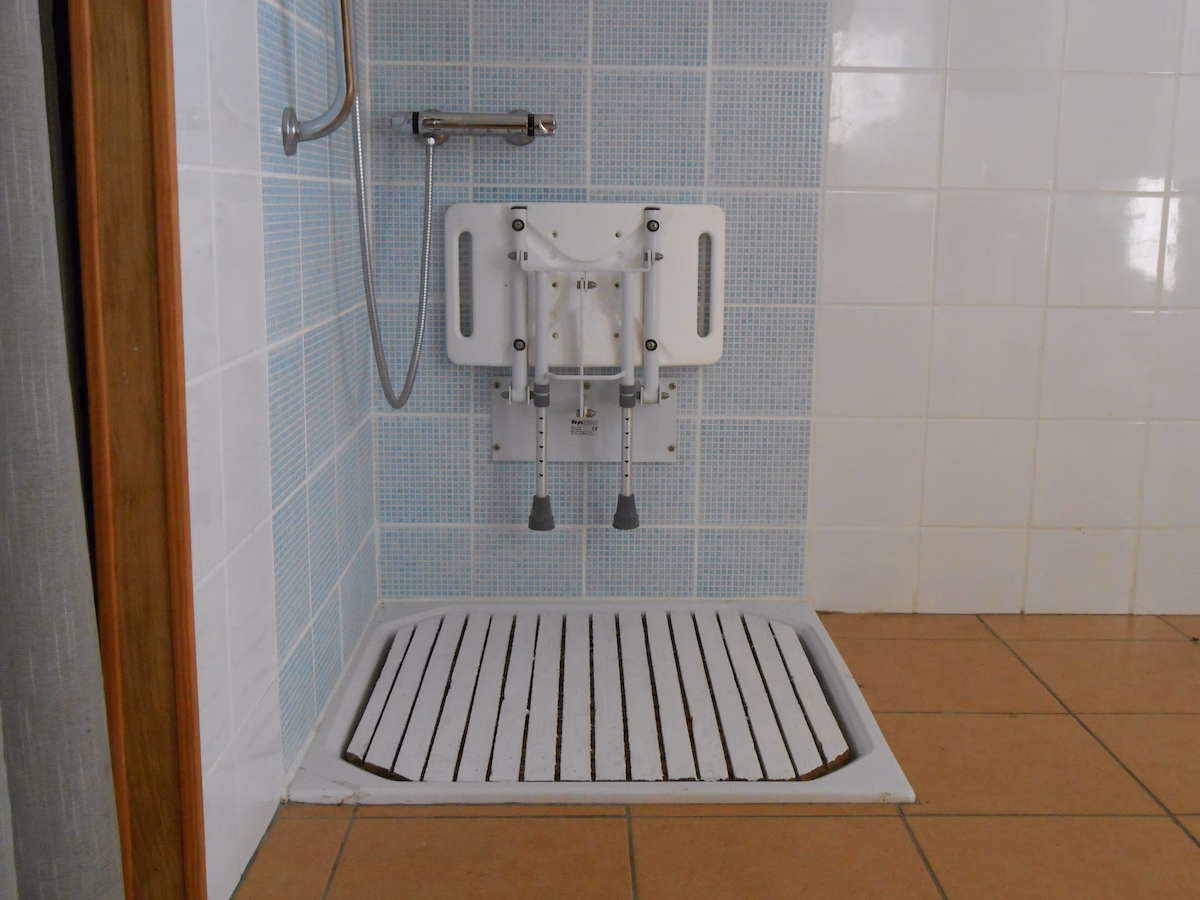 Accessible shower with folding seat and grab bar